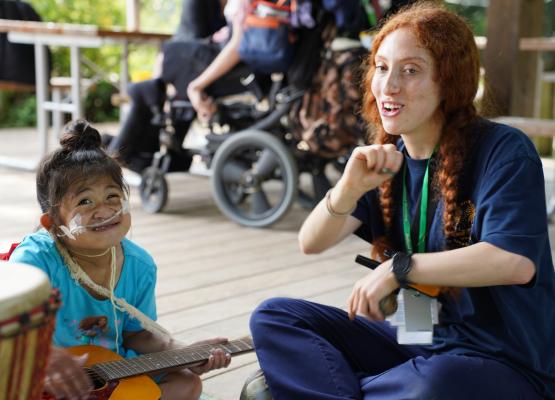 girl wearing nasal prongs holds guitar and sings with woman