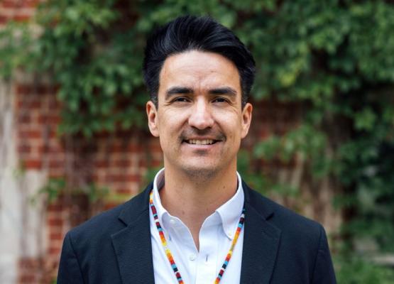 Man with dark hair and colourful necklace