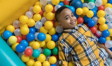 Young boy laying in ball pit 