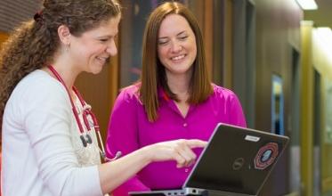 Two staff members looking at a laptop