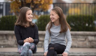 Two girls sitting on a wooden bench