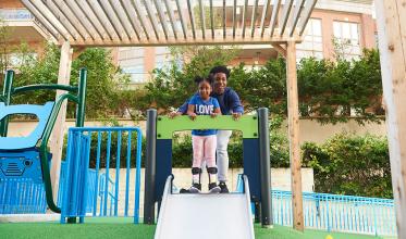 A youth holding a disability child and get ready to slide in a playground