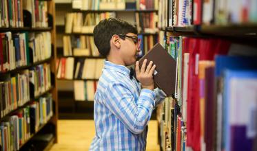 A child putting back a book onto the shelf in a library