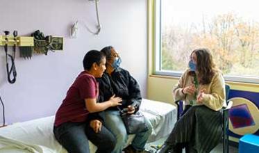Three adults in a hospital room setting