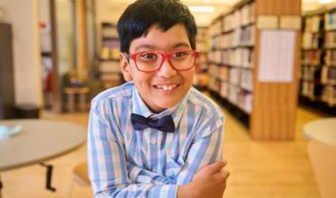A child with smile on the face, in front of a library setting