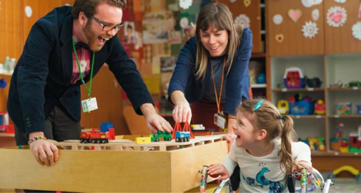 little girl and a man playing trains together