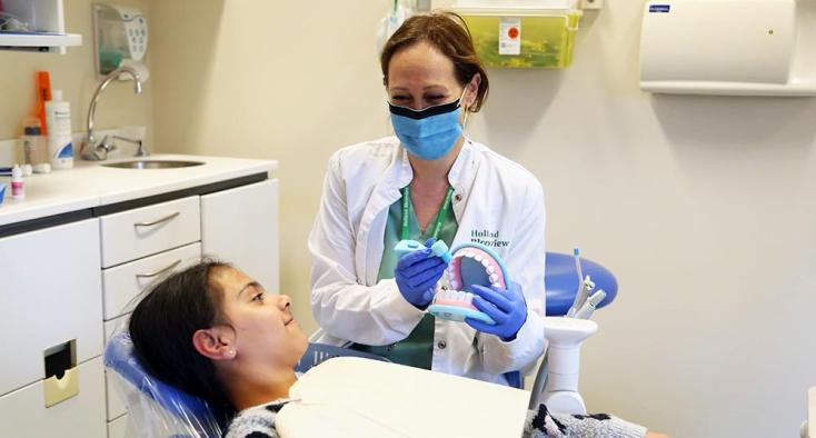 A dentist is explaining to a young patient about how to correctly brushing teeth