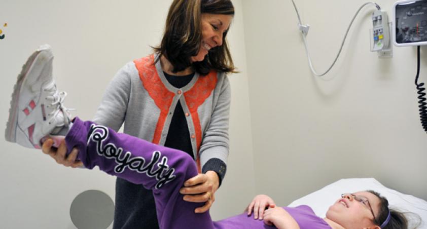 Female staff helping a girl lift her leg