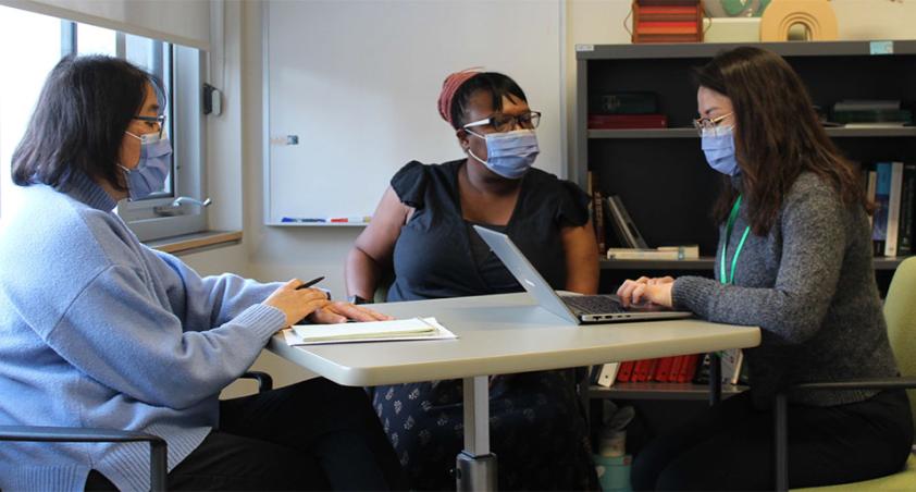 Three adults with mask on, having a meeting and discussion