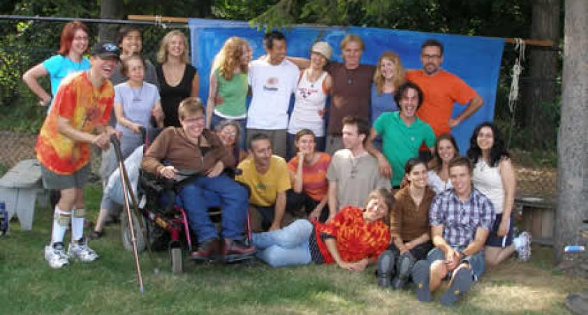 A group of staff, children and youth, including one in a wheelchair, standing by a fence.