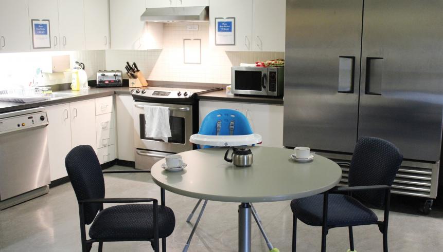 Communal kitchen area with dining table, dishwasher, sink, stove, and fridge