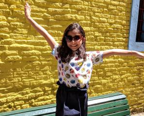 Rhea standing in front of a yellow brick wall