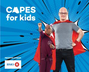 Image of adult man and younger male child posing as superheroes against blue backdrop that says "Capes for Kids"