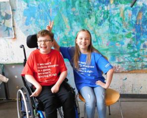 Two kids, one of whom uses a wheelchair, laughing