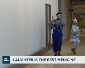 Two of our therapeutic clowns dancing and playing ukulele in a Holland Bloorview hallway