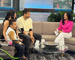 A TV shows with 3 adults and a child with a walker on the side.