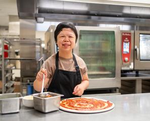 A kitchen staff making pizza