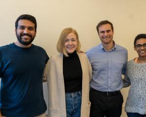 Four residents stand smiling against a beige wall 