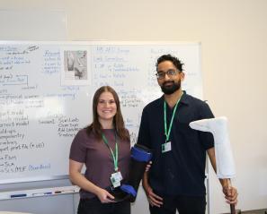 Elaine (left) and Harry (right) standing in front of a whiteboard, holding a prosthetic mould.