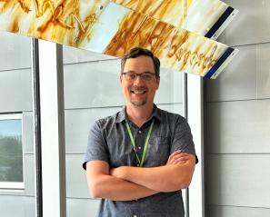 Dr. Jacob Ellegood has been named as the Bloorview Research Institute's new neuroimaging scientist. Image of light-skinned male adult standing by a window with arms crossed, wearing a grey dress shirt.