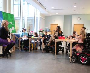 An adult is giving a talk to some children and two adults in an indoor setting