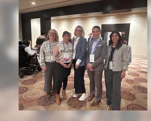 A group photo of 5 people in a conference