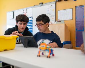 A teenager is helping a child to build a construction toy
