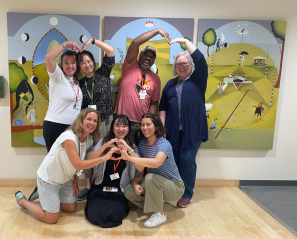 group of adults are smiling and posing for a photo against artwork in the background