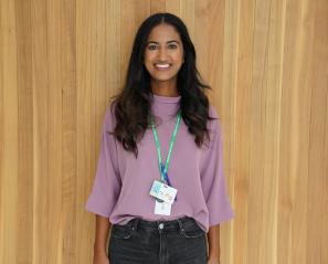 Woman with long dark hair and purple shirt wearing a green lanyard