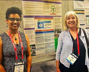 Dr. Selamesh Tsige-Legas and Dr. Darcy Fehlings stand in front of a research poster
