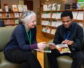 Two adults reading leaflets in a library setting