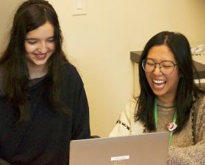 Teen girl and woman laugh at computer screen