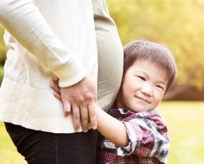 Boy hugs belly of pregnant woman