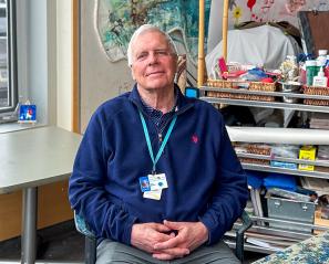 A man sits in an art therapy room with his hands in his lap. 