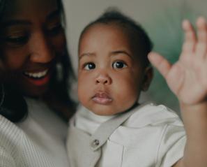 Baby waves in woman's arms
