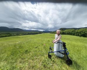 A child with walker is in the grass field