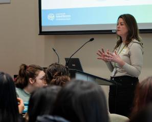 A speaker standing in front of a group of people, in a talk