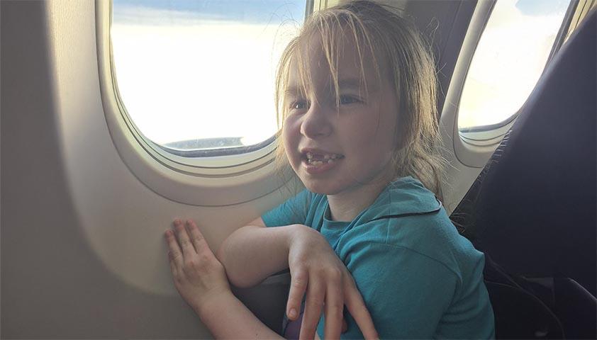 A girl sits beside an airplane window