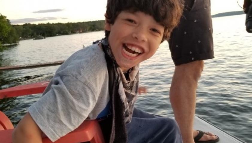 Joseph sitting on a chair on the dock at the cottage. 