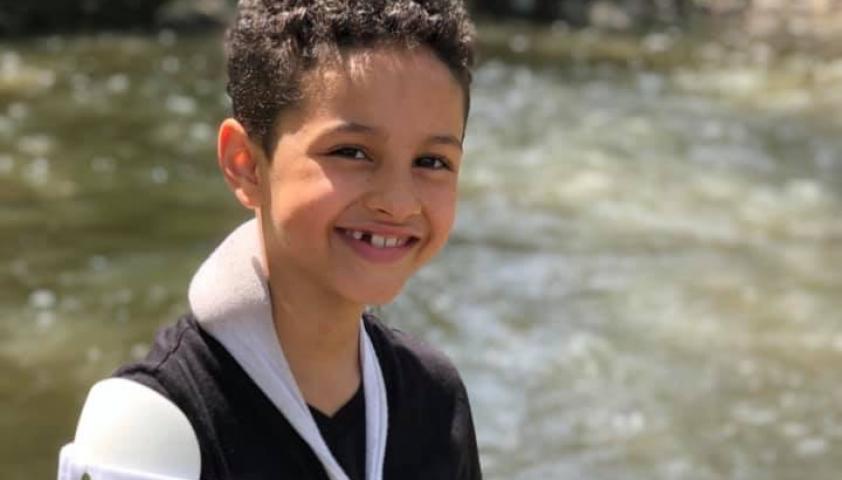 Zion smiling to the camera by a river.