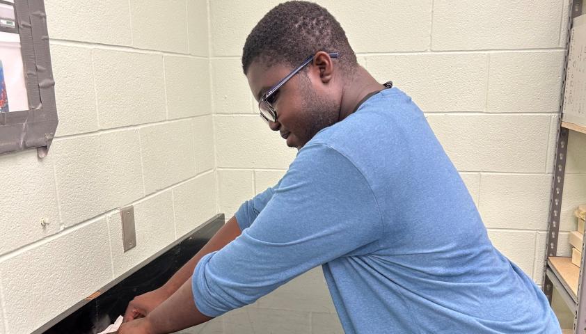 Isaiah wiping a counter at work