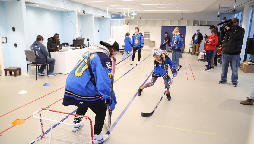 A child shooting a puck at a hockey net and goalie.