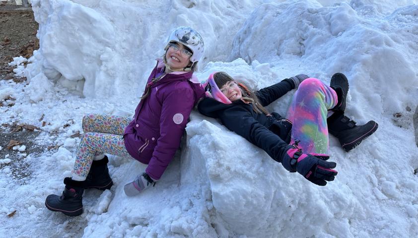 Two children playing in a pile of snow.