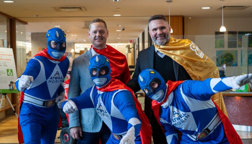 A group of adults dressed as superheroes and wearing red capes.