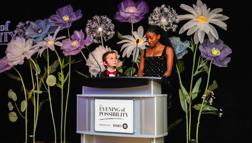 Two young people standing at a podium wearing formal clothing.