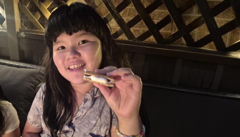 A child is holding a dessert on her hand