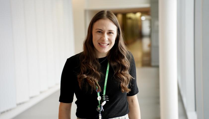 A female adult who is a nurse practitioner stands in a hallway