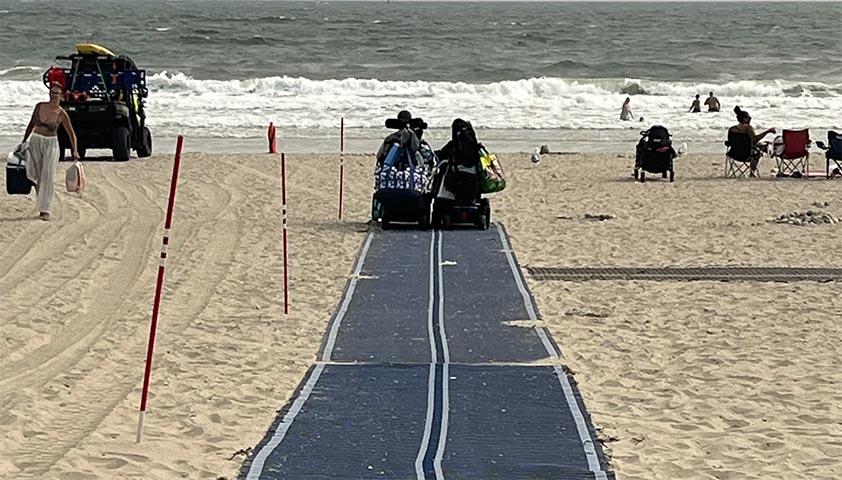 Two teenagers are riding their wheelchair approaching a beach
