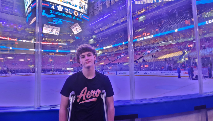 A teenage boy who used crutches stands in front of an ice rink