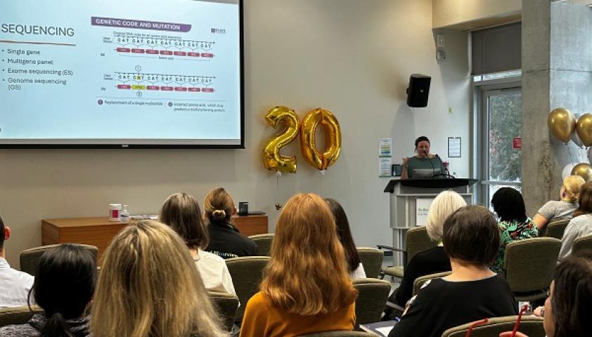 Adult woman presents in front of a podium to an audience